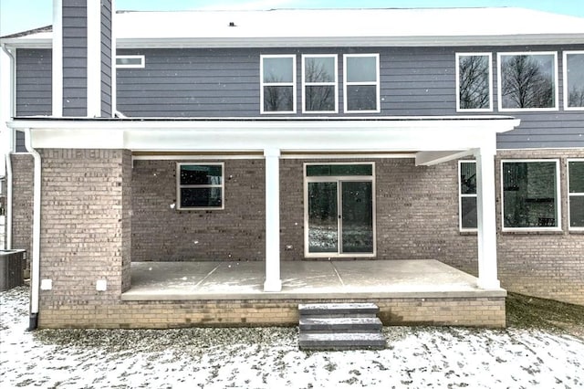 snow covered back of property featuring cooling unit