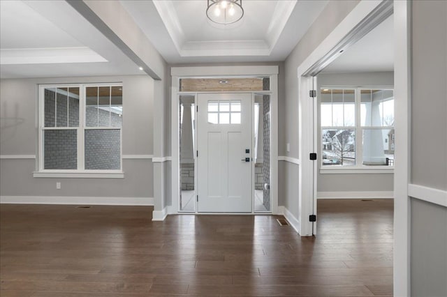 entrance foyer featuring a raised ceiling, crown molding, and dark hardwood / wood-style floors