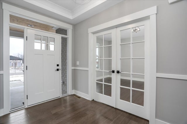 foyer entrance with dark hardwood / wood-style floors, ornamental molding, and french doors