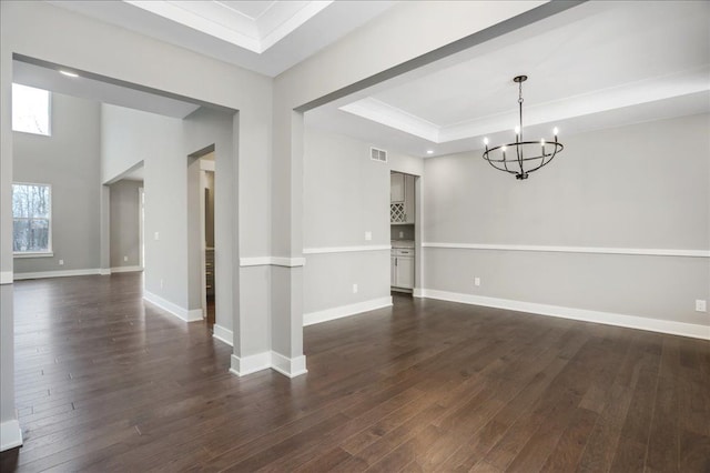 unfurnished dining area featuring an inviting chandelier, dark hardwood / wood-style flooring, crown molding, and a tray ceiling