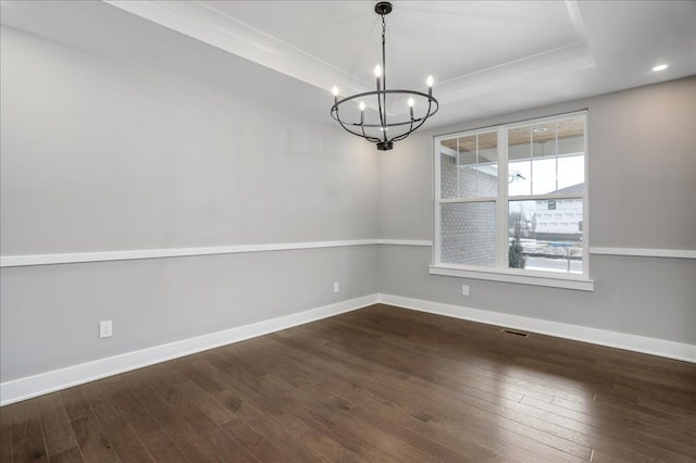 unfurnished dining area with a notable chandelier, dark hardwood / wood-style floors, ornamental molding, and a tray ceiling