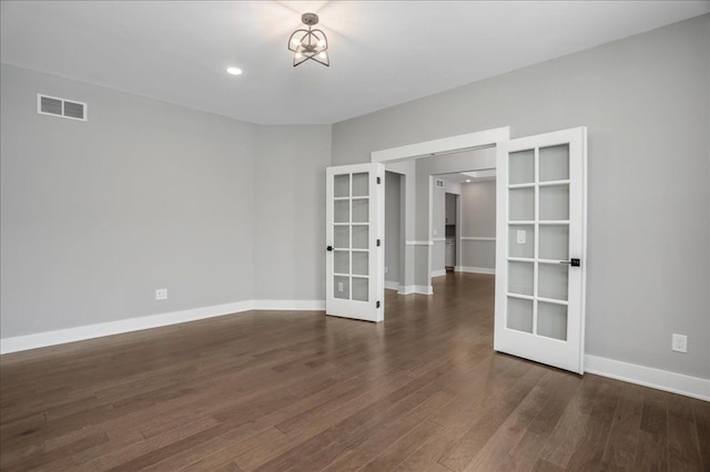 empty room with french doors, dark hardwood / wood-style floors, and a notable chandelier