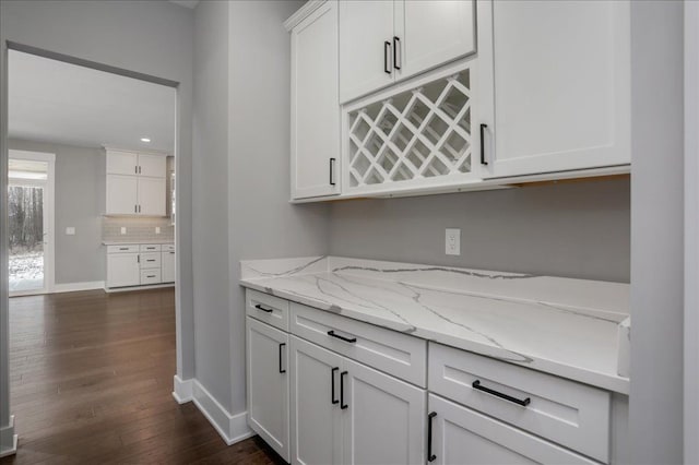 bar featuring dark hardwood / wood-style floors, light stone counters, white cabinetry, and tasteful backsplash