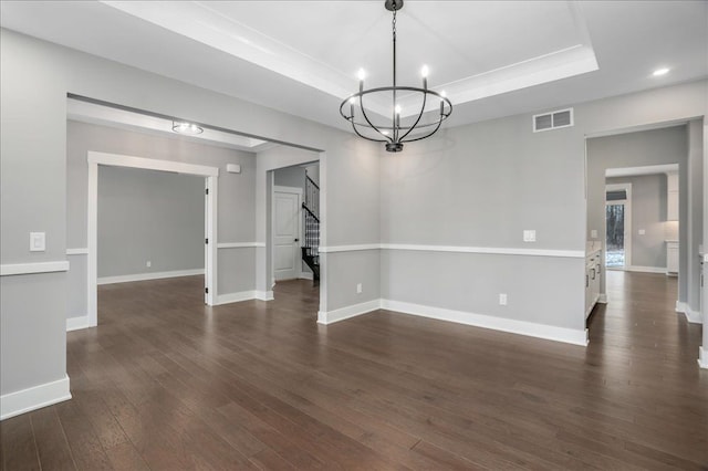 spare room with a notable chandelier, dark hardwood / wood-style flooring, and a raised ceiling