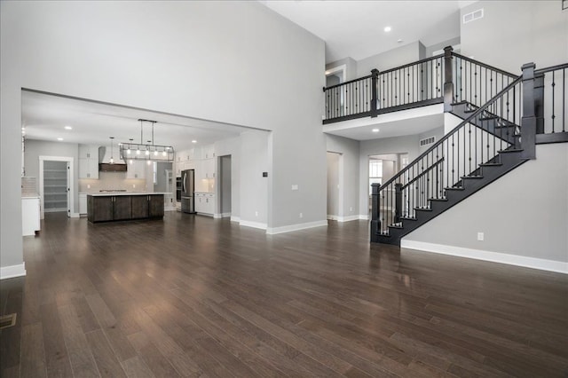 unfurnished living room featuring dark hardwood / wood-style flooring and a towering ceiling