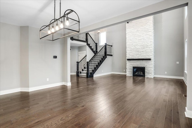 unfurnished living room featuring a fireplace, dark hardwood / wood-style flooring, and a chandelier