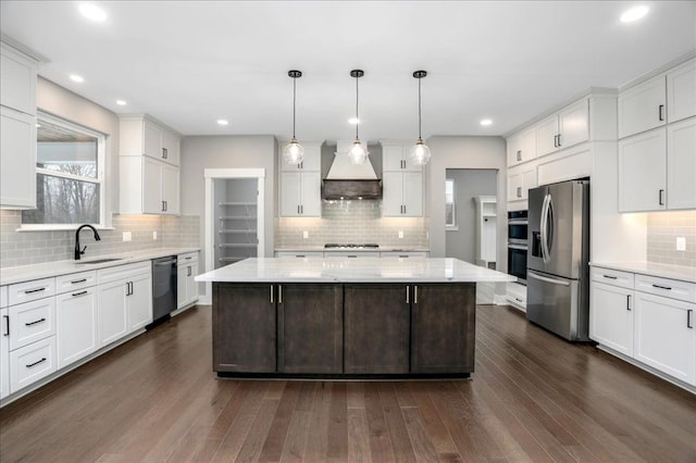 kitchen featuring appliances with stainless steel finishes, decorative light fixtures, a kitchen island, and custom exhaust hood