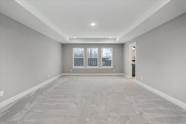 carpeted spare room featuring a tray ceiling