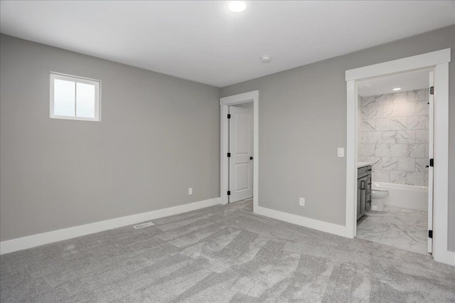 unfurnished bedroom featuring light carpet and ensuite bath