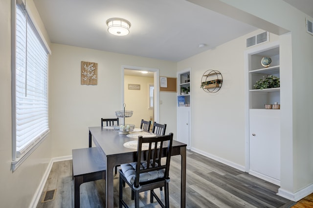 dining area featuring built in shelves and dark wood-type flooring