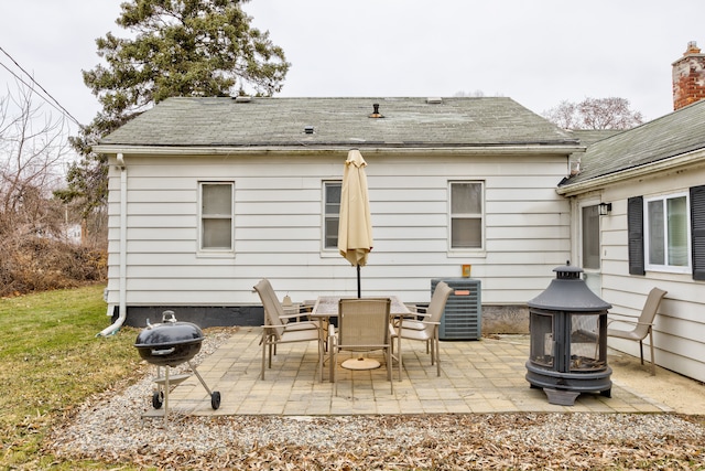 rear view of property featuring a patio, central AC unit, and an outdoor fire pit