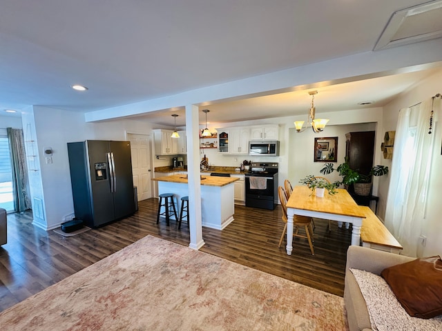 kitchen featuring wood counters, a center island, hanging light fixtures, appliances with stainless steel finishes, and white cabinetry