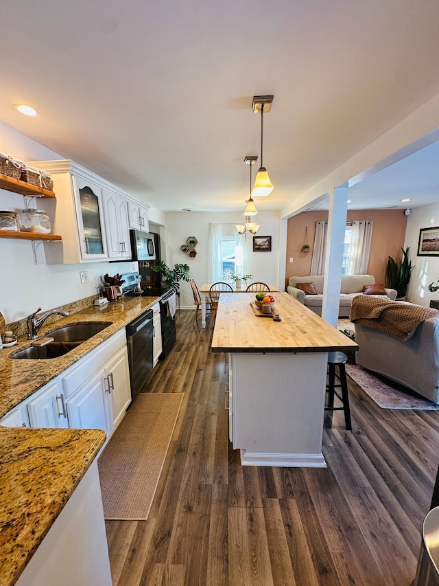 kitchen featuring sink, dishwasher, white cabinetry, hanging light fixtures, and a breakfast bar area