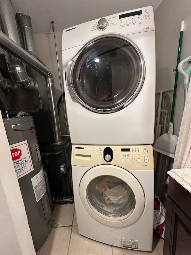 washroom with electric water heater, light tile patterned floors, and stacked washer and clothes dryer