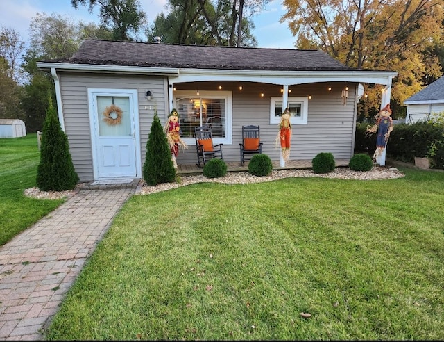 single story home with an outbuilding, covered porch, and a front lawn