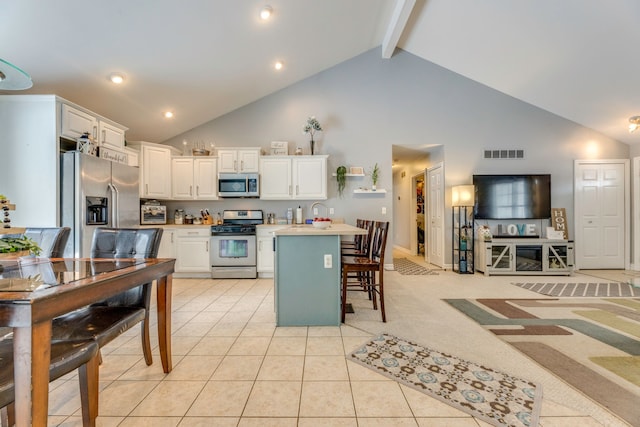 kitchen with white cabinets, appliances with stainless steel finishes, a kitchen bar, and beamed ceiling