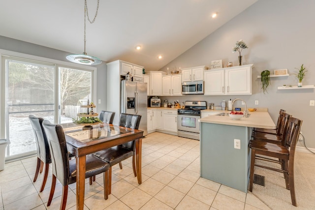 kitchen featuring a kitchen breakfast bar, kitchen peninsula, pendant lighting, white cabinets, and appliances with stainless steel finishes