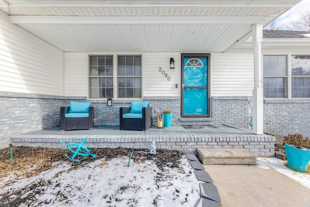 snow covered property entrance with covered porch