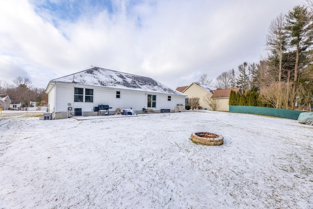 snow covered back of property with a fire pit