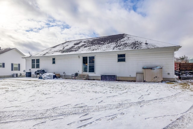 snow covered back of property featuring central AC unit