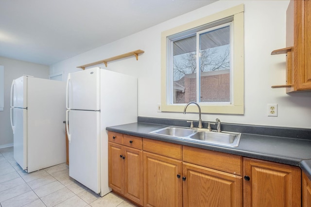 kitchen with light tile patterned floors, white fridge, and sink