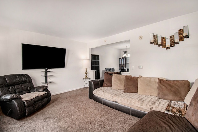 carpeted living room featuring a notable chandelier