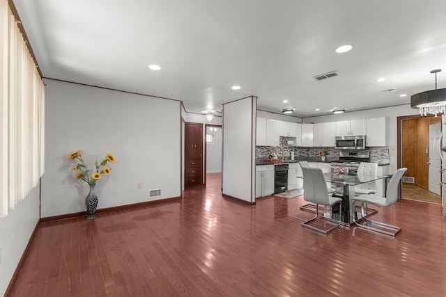 kitchen with white cabinetry, hanging light fixtures, decorative backsplash, a kitchen island, and appliances with stainless steel finishes