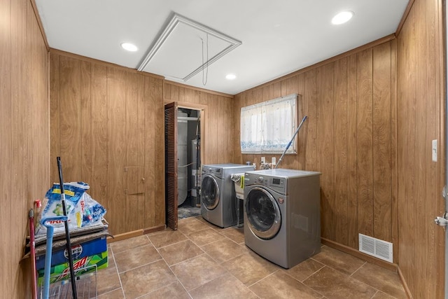 clothes washing area featuring independent washer and dryer and wooden walls