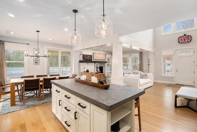 kitchen featuring hanging light fixtures, a kitchen island, a healthy amount of sunlight, and light wood-type flooring