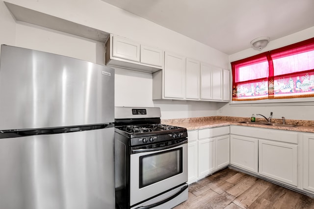 kitchen with sink, white cabinets, light hardwood / wood-style flooring, and appliances with stainless steel finishes