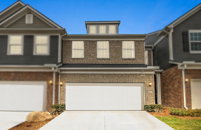 view of property featuring stone siding, an attached garage, and driveway