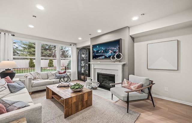 living room featuring light wood-type flooring, recessed lighting, baseboards, and a fireplace