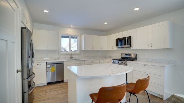 kitchen with white cabinets, a kitchen island, sink, and appliances with stainless steel finishes