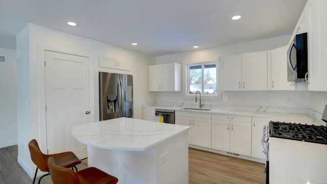 kitchen with light stone countertops, stainless steel appliances, white cabinetry, and sink