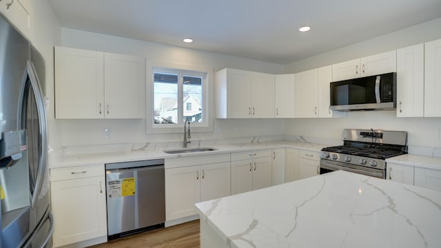 kitchen with white cabinets, light stone countertops, sink, and appliances with stainless steel finishes