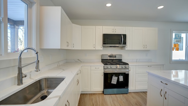 kitchen featuring appliances with stainless steel finishes, white cabinetry, and sink