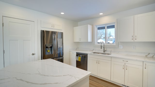 kitchen featuring sink, light wood-type flooring, appliances with stainless steel finishes, light stone counters, and white cabinetry