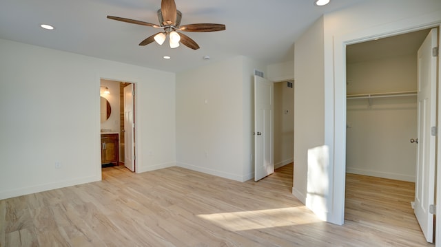 unfurnished bedroom featuring ensuite bathroom, ceiling fan, a spacious closet, light hardwood / wood-style floors, and a closet