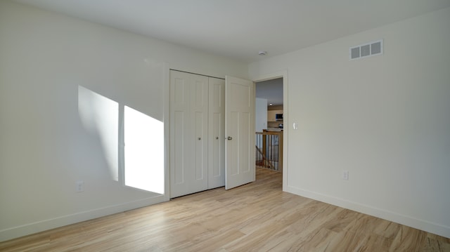 unfurnished bedroom with a closet and light wood-type flooring