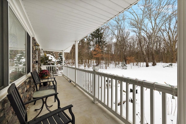 snow covered back of property featuring a porch