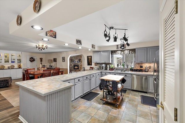 kitchen featuring tasteful backsplash, tile countertops, dishwasher, gray cabinets, and a kitchen island