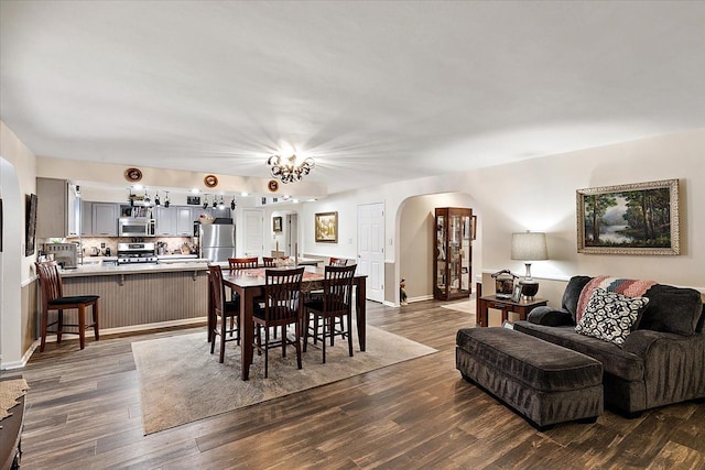 dining area with dark wood-type flooring and an inviting chandelier