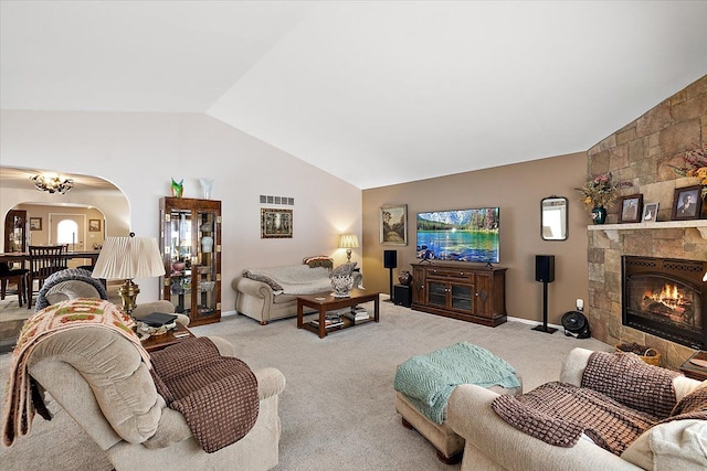 carpeted living room with a stone fireplace and lofted ceiling