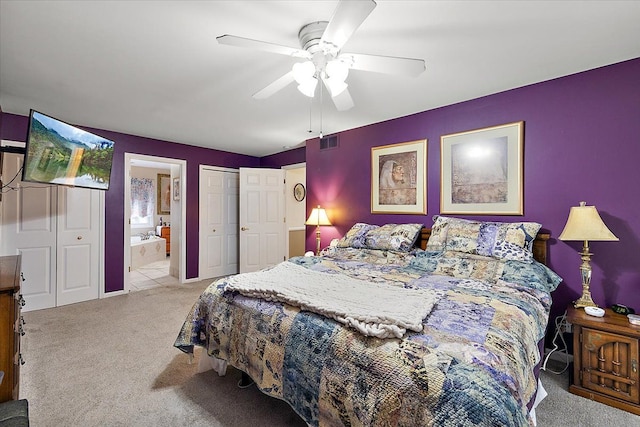 carpeted bedroom with ensuite bathroom and ceiling fan