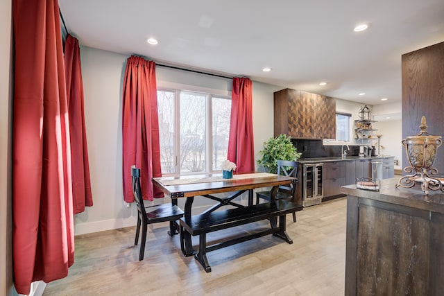 dining area with wine cooler, sink, and light wood-type flooring