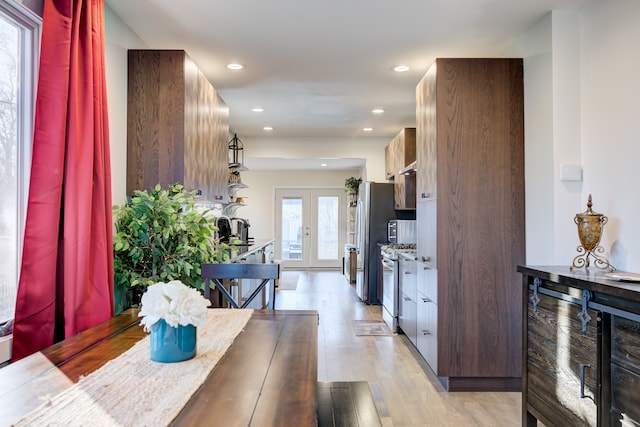 dining room featuring french doors, light hardwood / wood-style flooring, and a healthy amount of sunlight