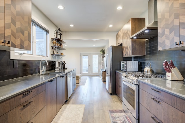 kitchen with stainless steel counters, french doors, wall chimney exhaust hood, stainless steel appliances, and sink