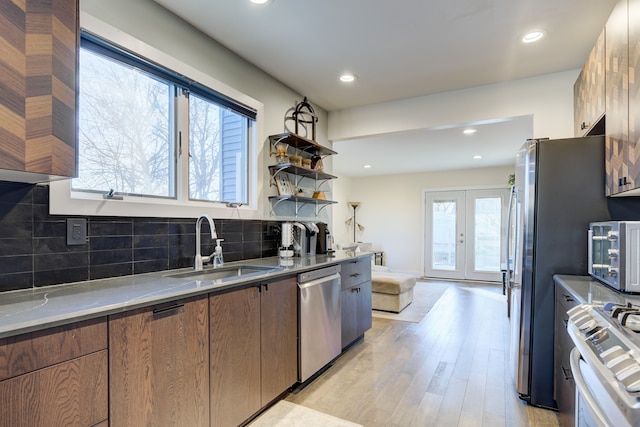 kitchen with decorative backsplash, stainless steel appliances, sink, light hardwood / wood-style flooring, and plenty of natural light