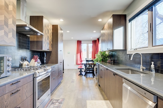 kitchen with sink, stainless steel appliances, extractor fan, light hardwood / wood-style floors, and decorative backsplash