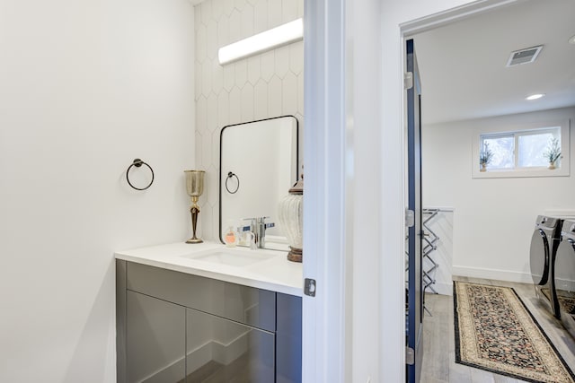 bathroom with washer and clothes dryer, vanity, and hardwood / wood-style flooring